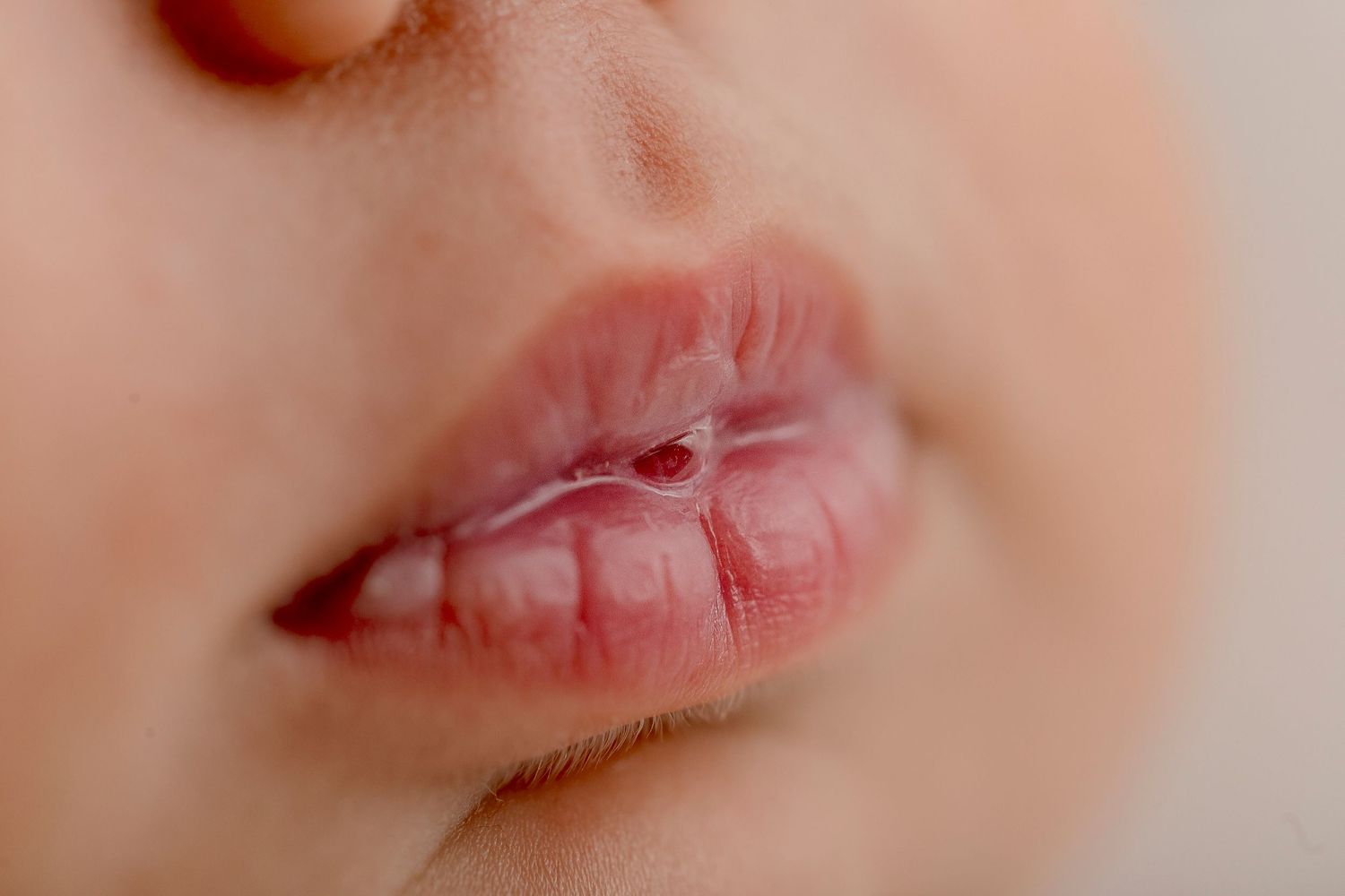 Extreme close-up of soft pink baby lips and skin.