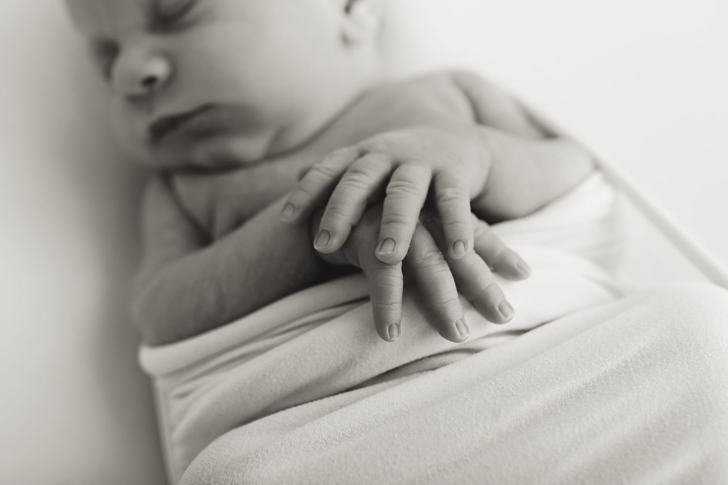 Series of intimate black and white newborn portraits with soft white wrapping.
