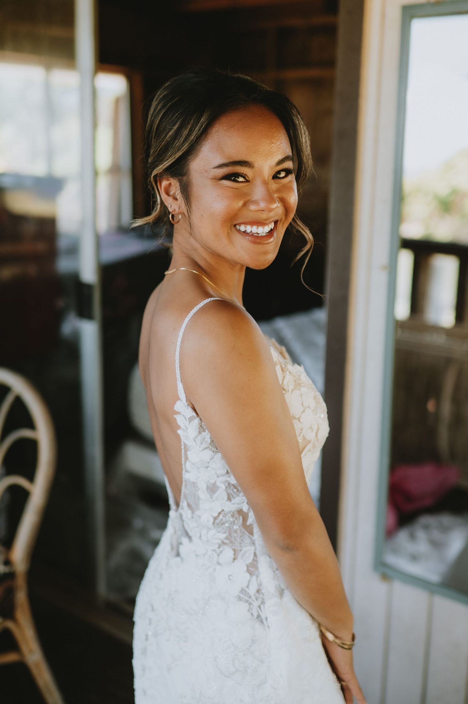 Bride in lace wedding dress smiles while getting ready.