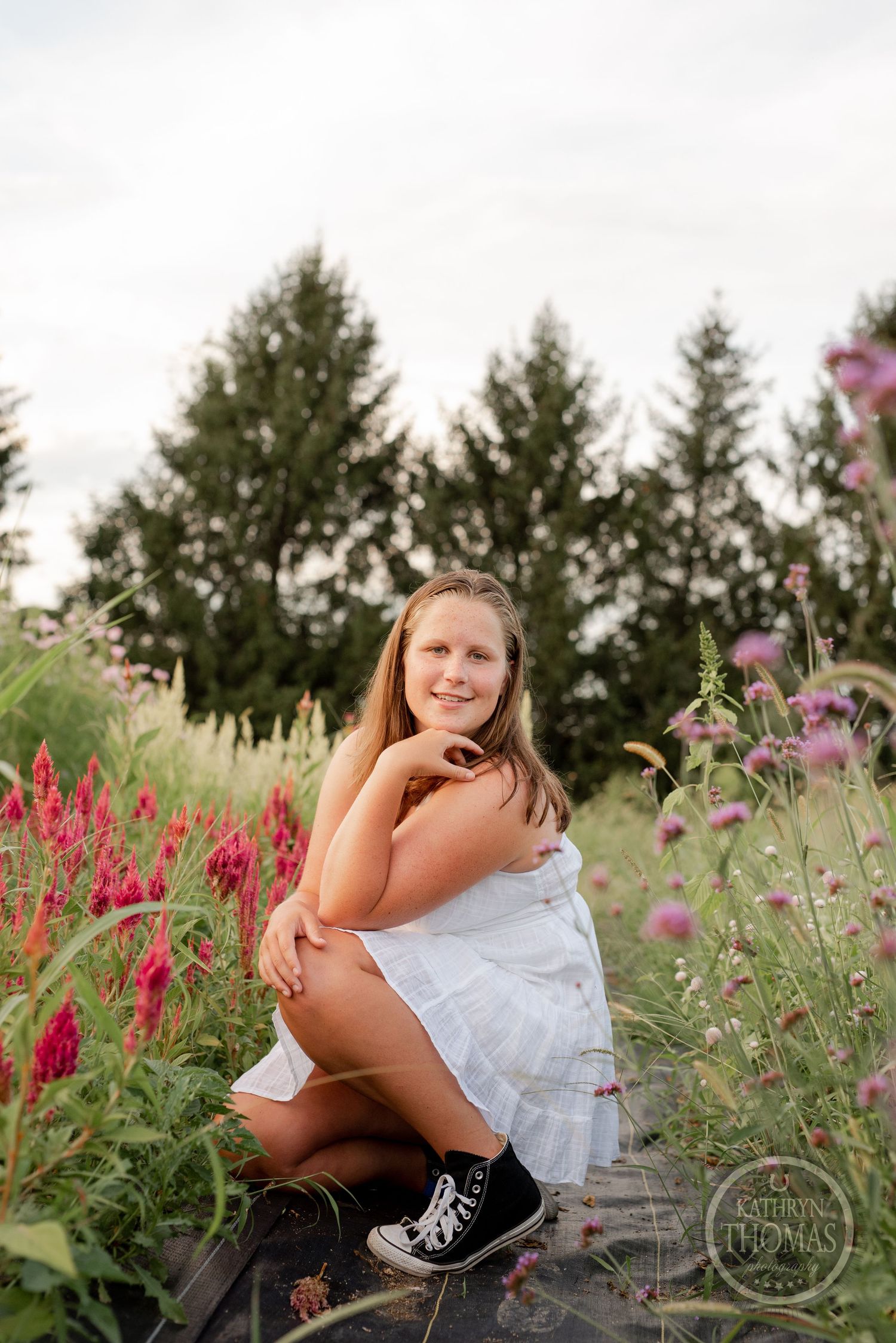 A playful pose among red and purple wildflowers with sneakers and a white dress.