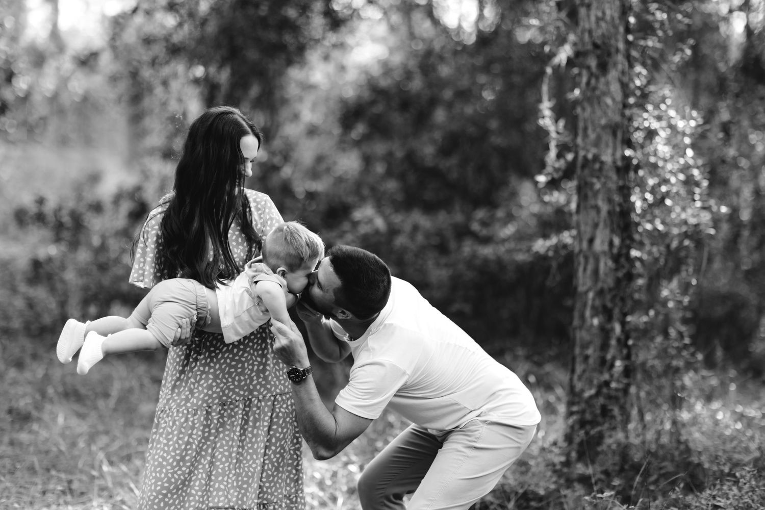 A joyful outdoor family photoshoot with playful moments in a wooded setting.