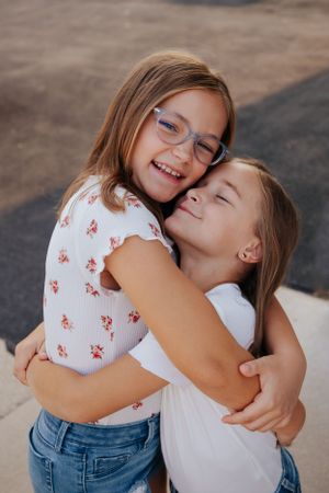 Two children sharing affectionate embrace and smiles outdoors.