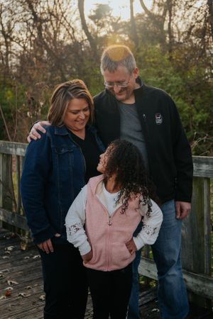 Family huddled together sharing warm embrace on wooden deck at sunset.