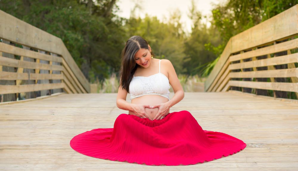 A woman in a red skirt is sitting on a bridge - Julio Naranjo Photography
