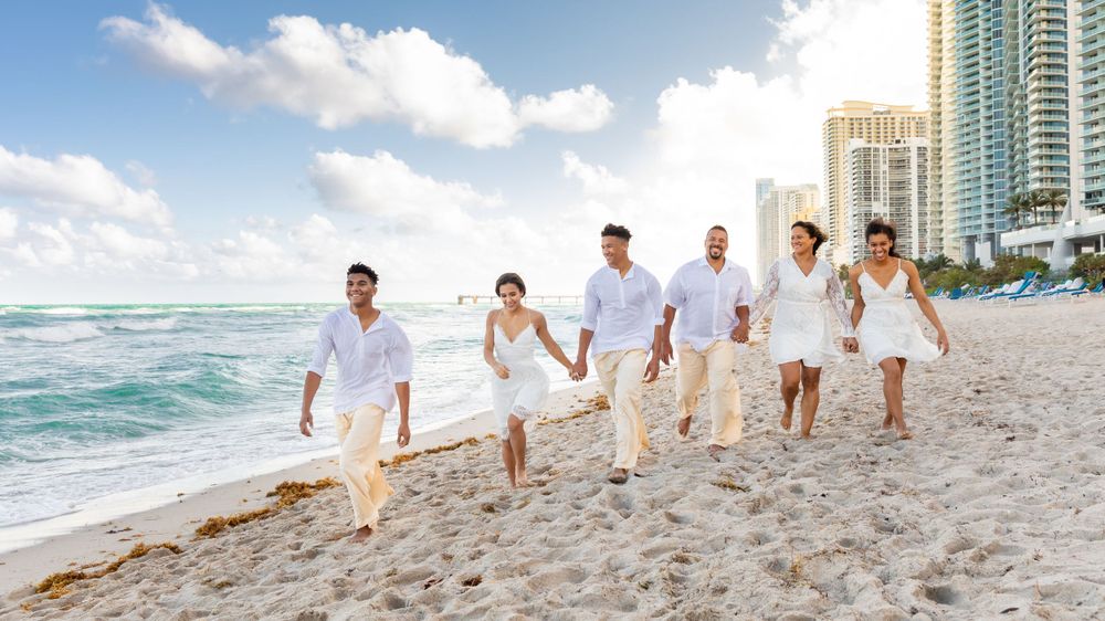 A group of people walking along a beach next to the ocean - Julio Naranjo Photography