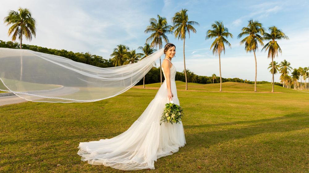 A woman in a wedding dress standing in a field - Julio Naranjo Photography