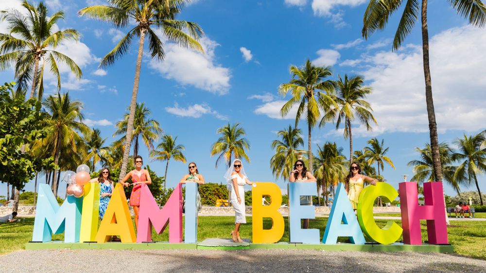 The word Miemi Beach spelled in multicolored letters in front of palm trees - Julio Naranjo Photography