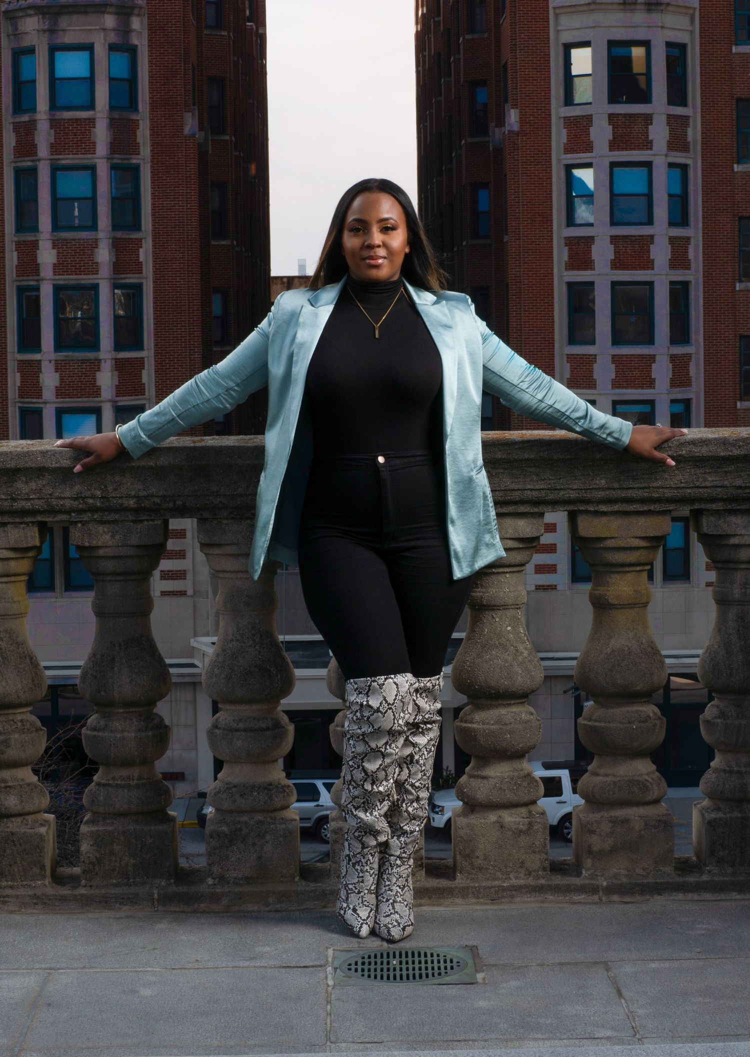 Urban fashion portrait on stone balcony wearing light blue blazer and snakeskin boots.