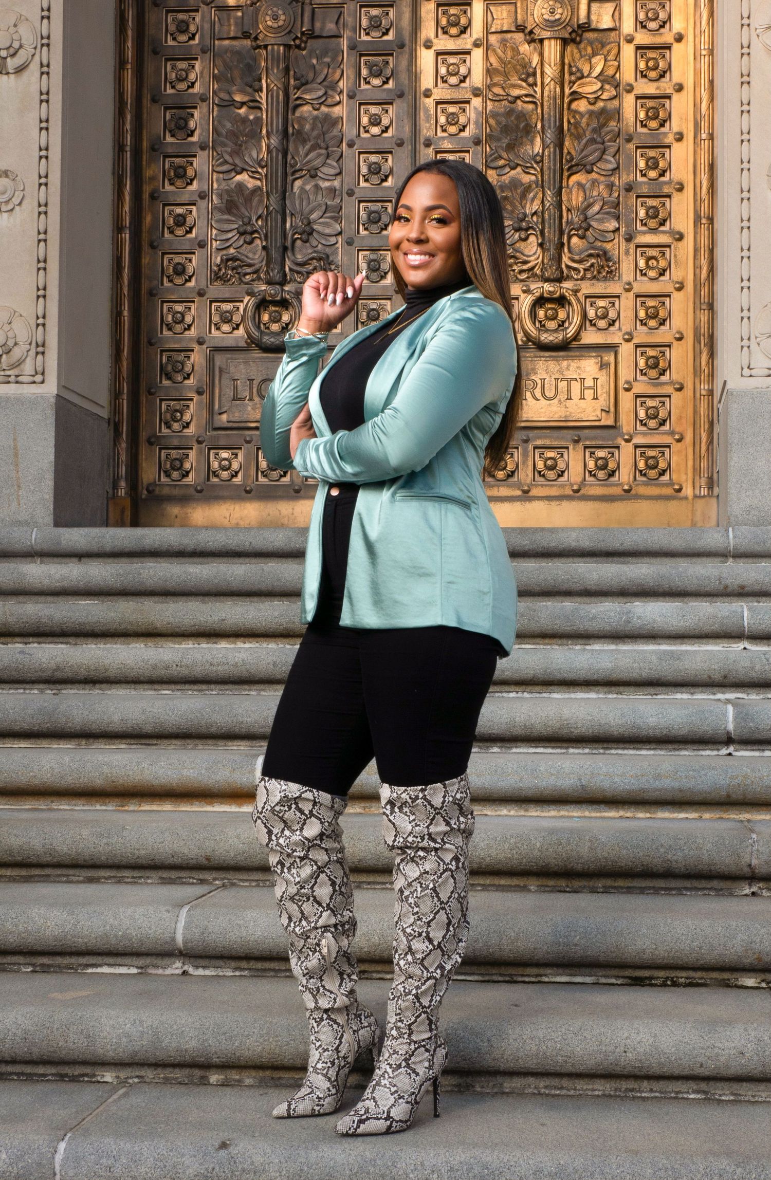 Stylish outfit featuring mint blazer and snakeskin boots on stone steps with ornate door backdrop.