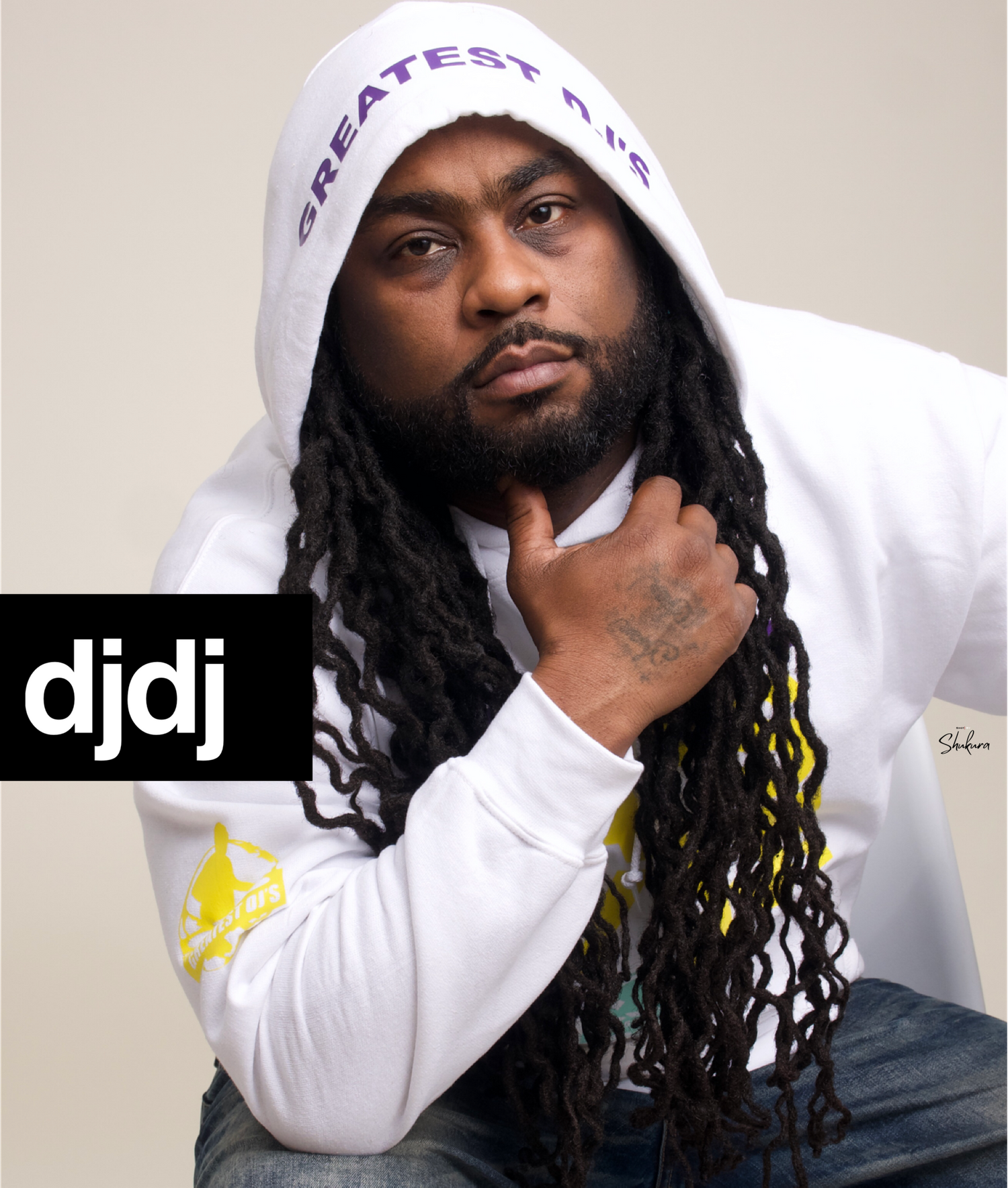 Artist in white hoodie with long hair poses against neutral background.