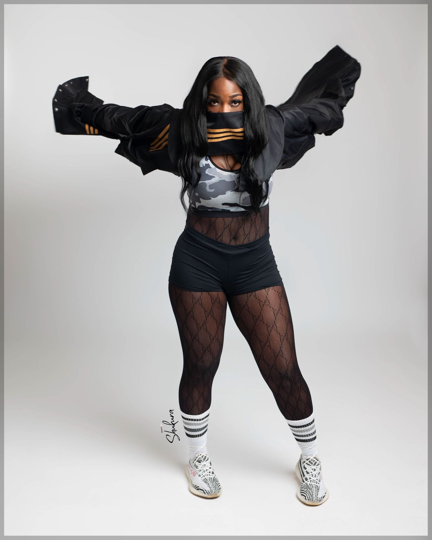 Dancer in black athletic wear and fishnet stockings strikes dynamic pose.