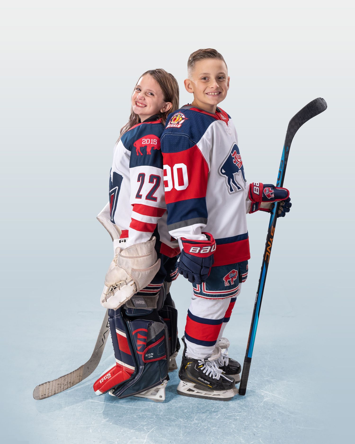Hockey players in blue and red jerseys pose together on white ice surface.