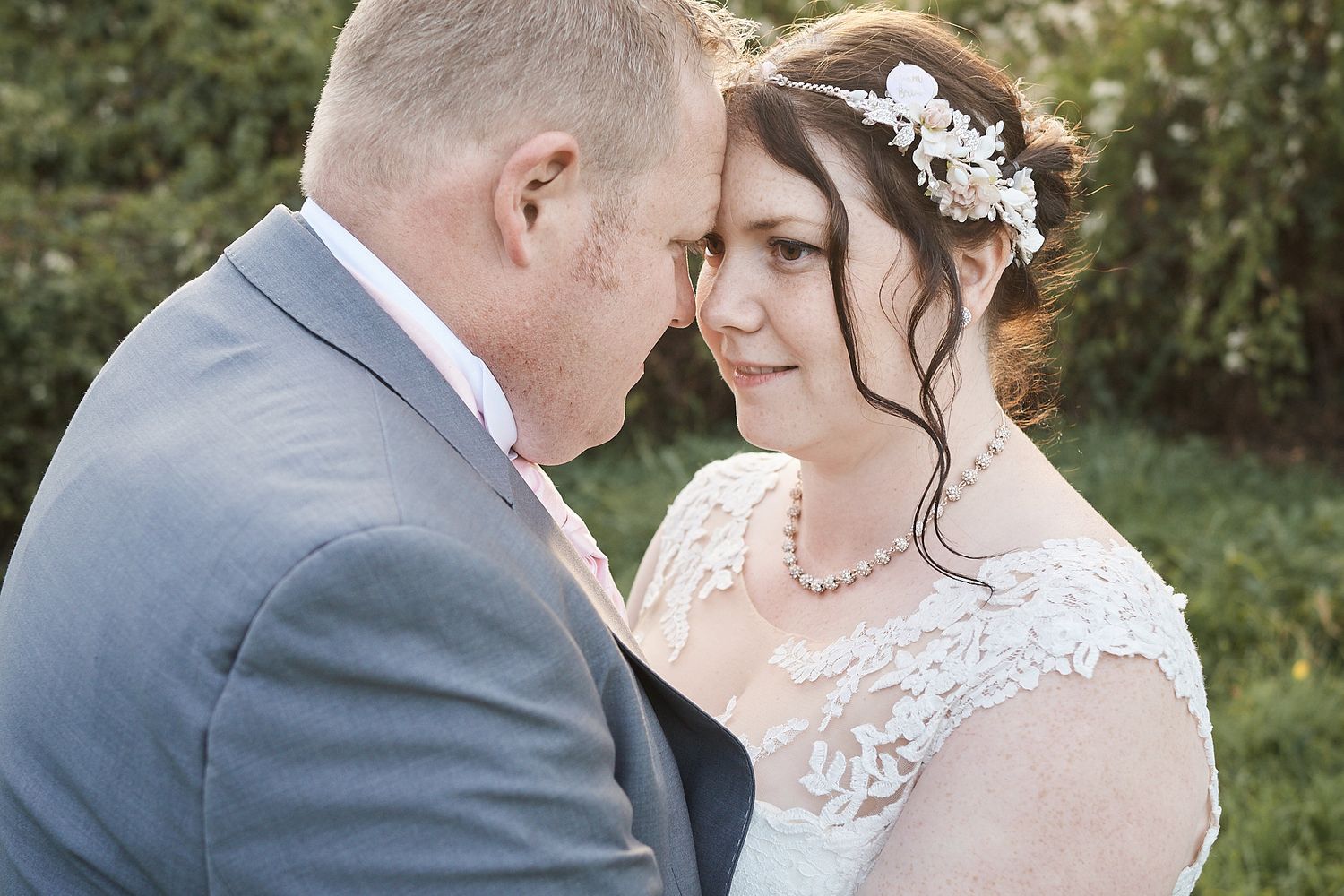 beautiful portrait of bride and groom bride wears lace dress with white floral hair piece by Norfolk wedding photography