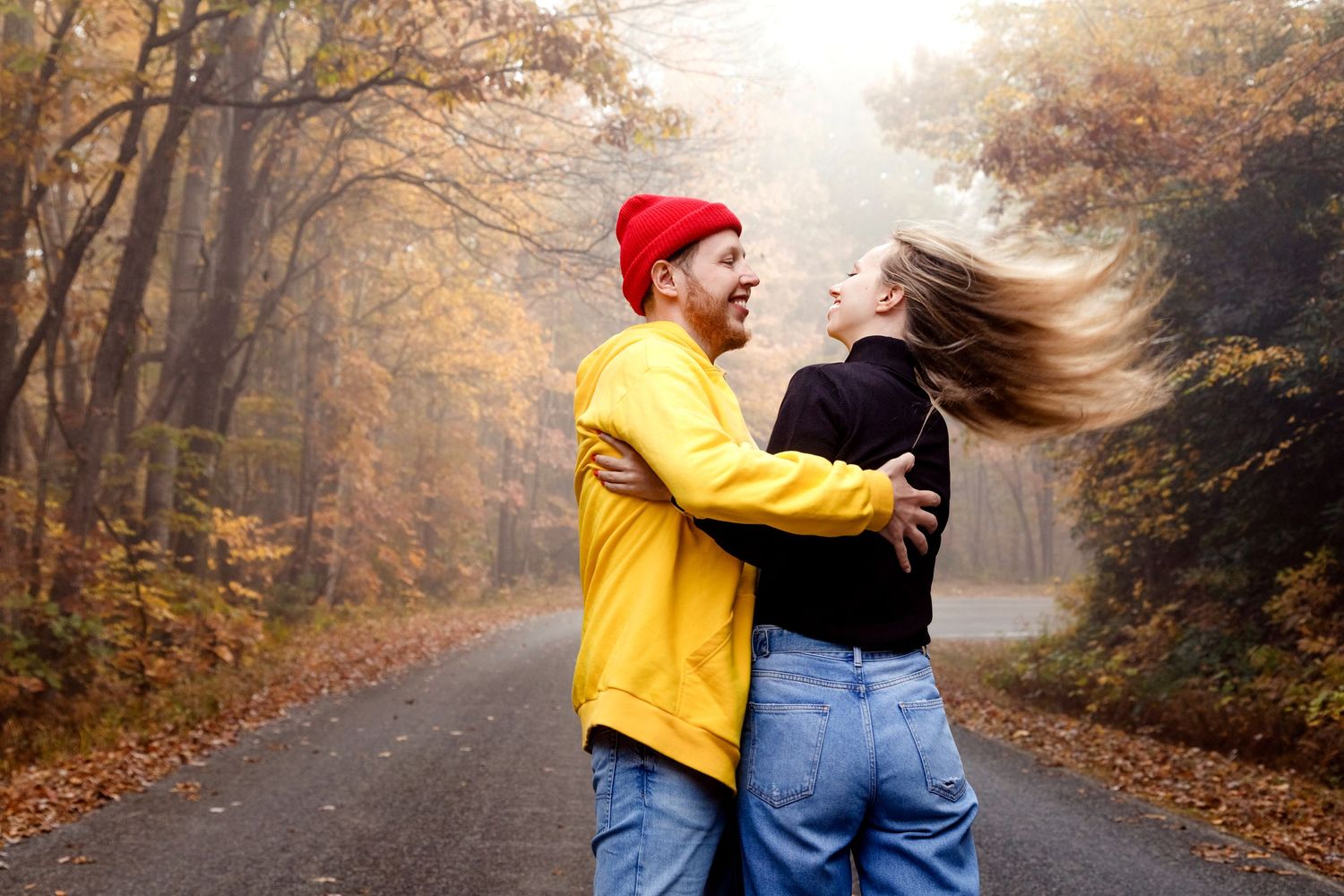 Playful moment captured on an autumn road with vibrant fall foliage and golden light.