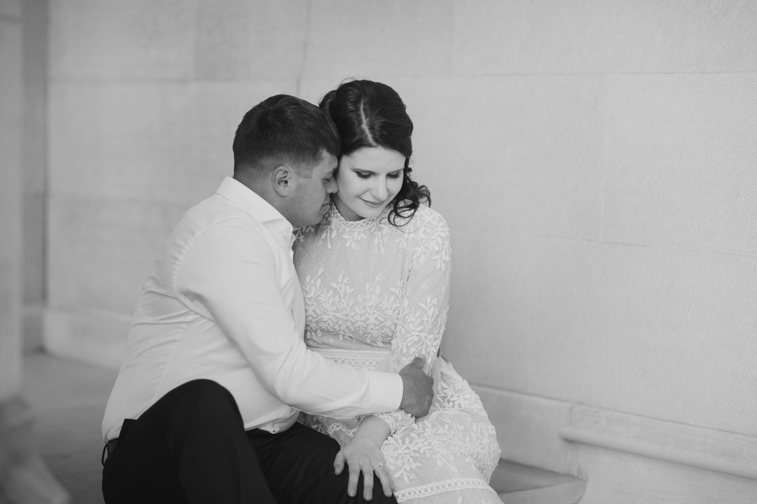An intimate black and white portrait of a couple sharing a quiet moment indoors.