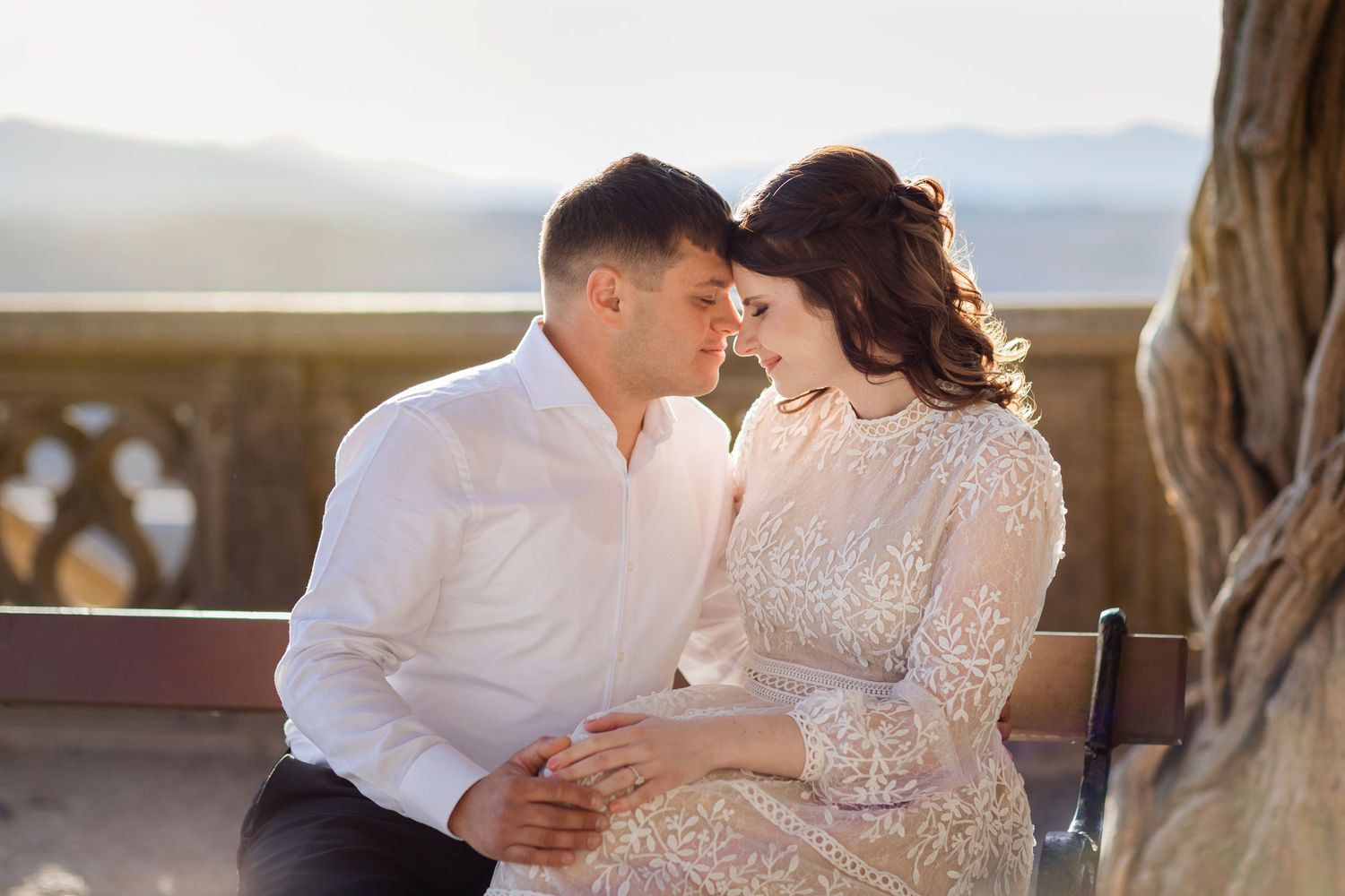 A couple shares an intimate moment on a bench during golden hour.