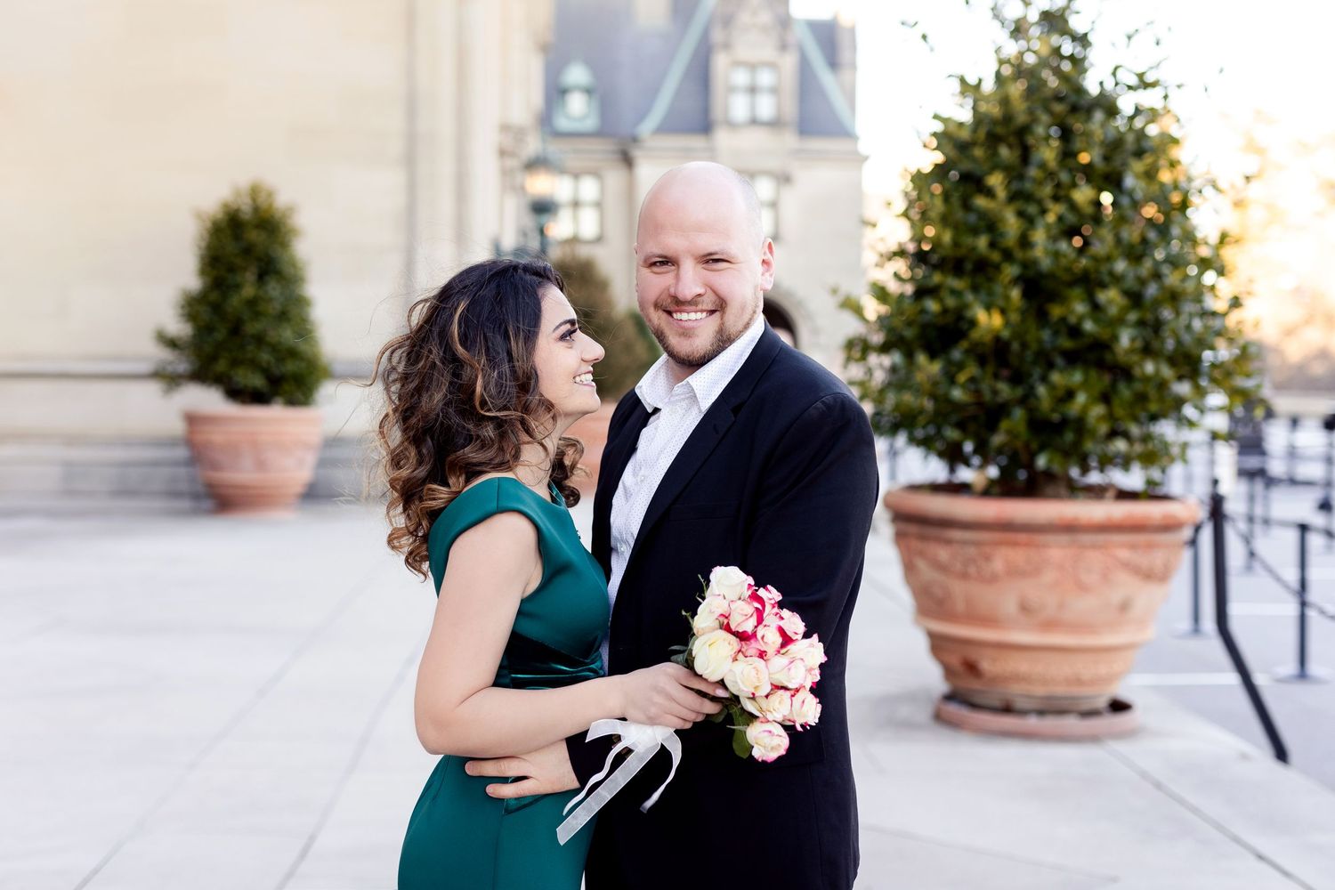A romantic moment shared on an elegant terrace with decorative potted plants.