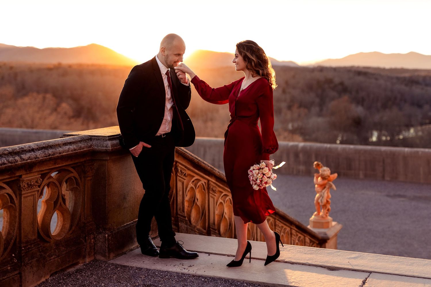 A romantic sunset moment on a stone balcony against a mountain backdrop.