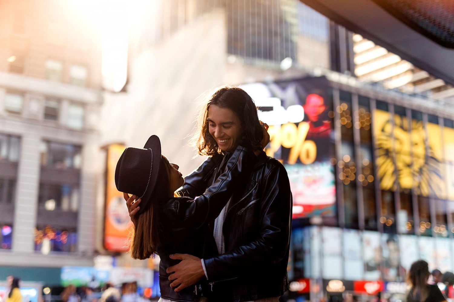 Intimate moment between couple illuminated by warm city lights in Times Square.