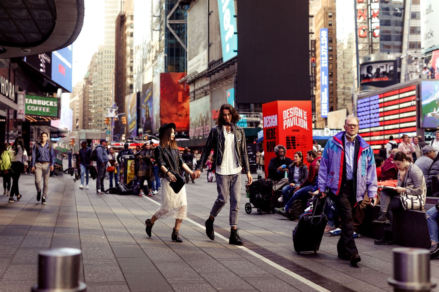 Couple walking through busy Times Square surrounded by bright city lights and crowds.