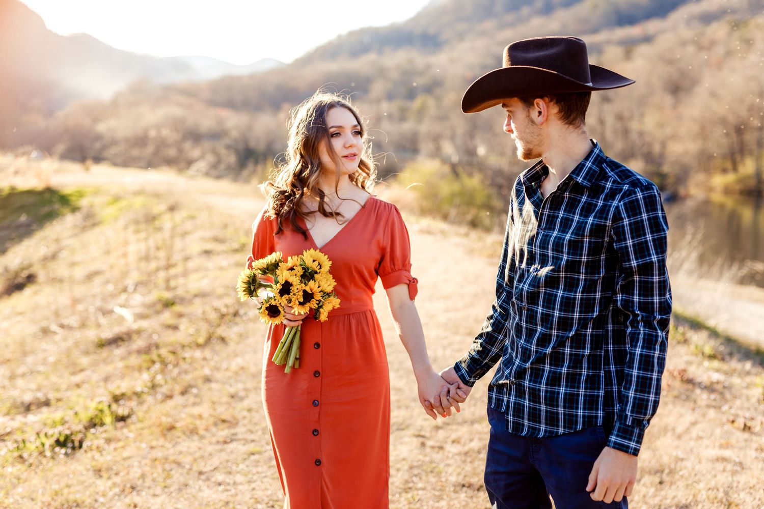 A romantic couple in a western-inspired setting with sunflowers and mountains in the background.