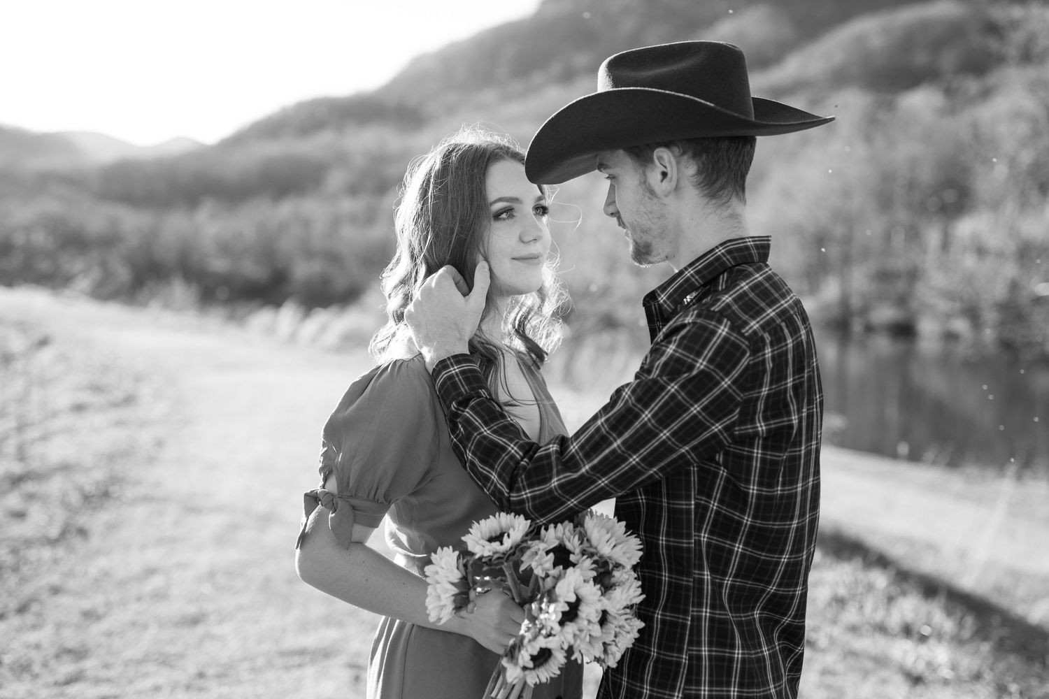 An intimate black and white portrait of a couple sharing a tender moment with wildflowers.
