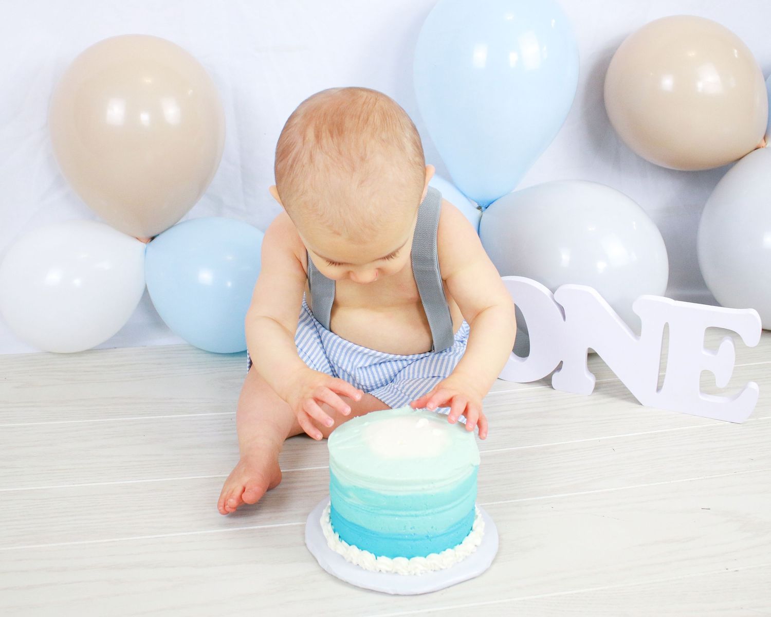Minimalist cake smash setup with blue and white balloons.
