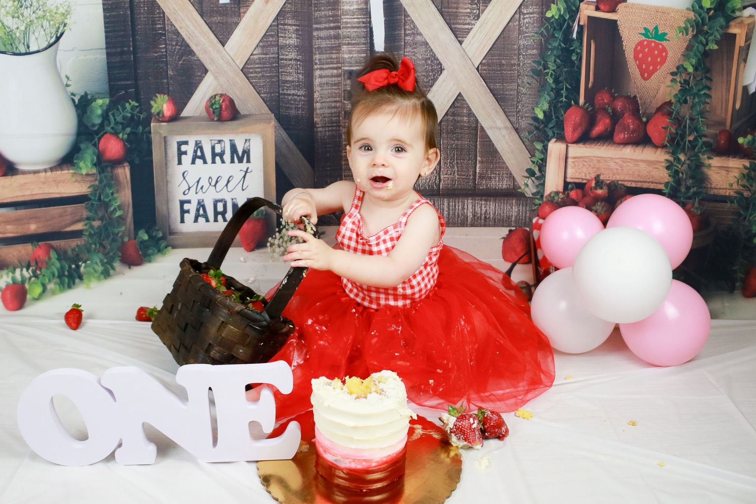First birthday celebration setup with red tulle dress and white balloons.