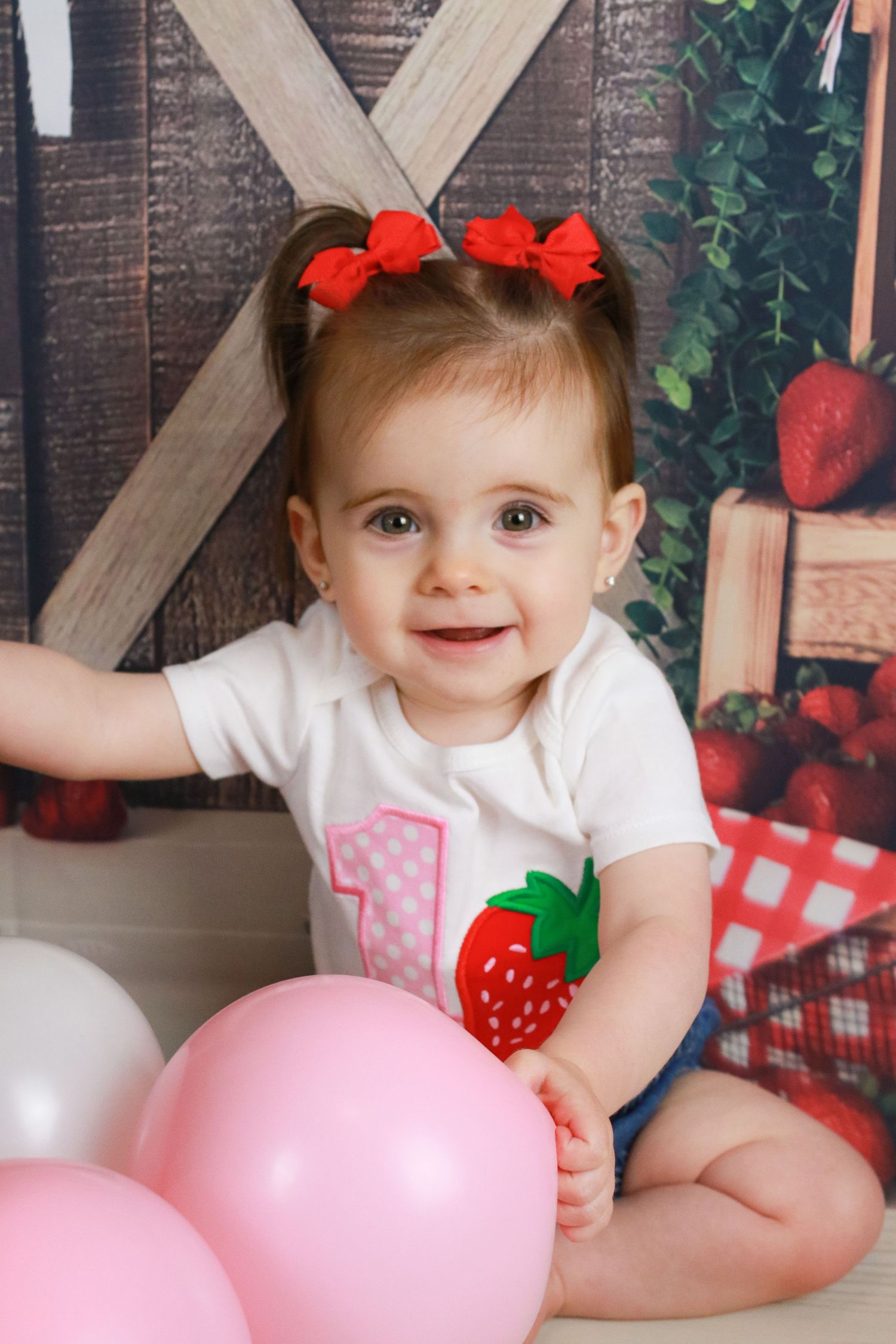 Strawberry themed first birthday photo session with pink balloons.