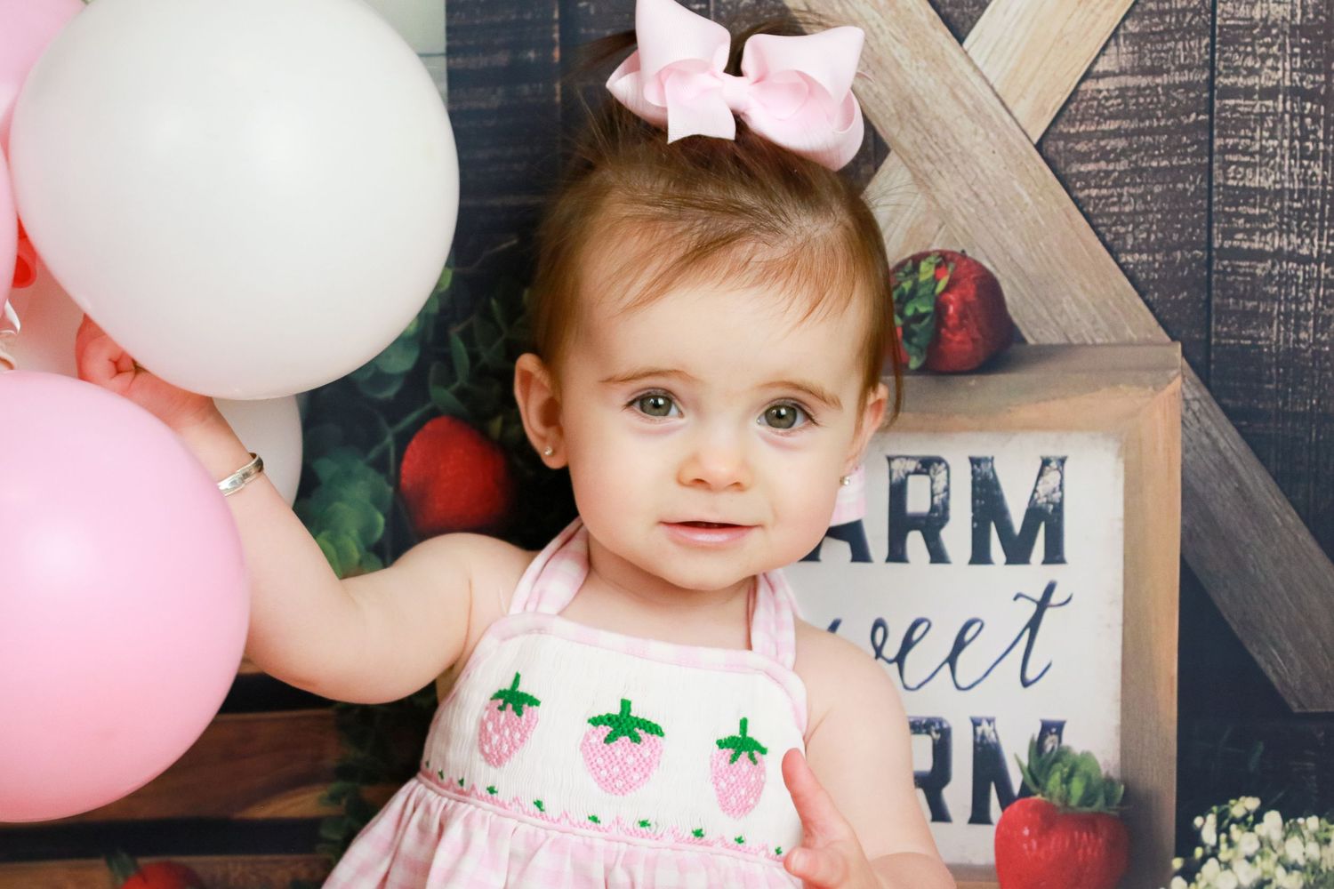 Pink and white themed birthday photo session with rustic backdrop.