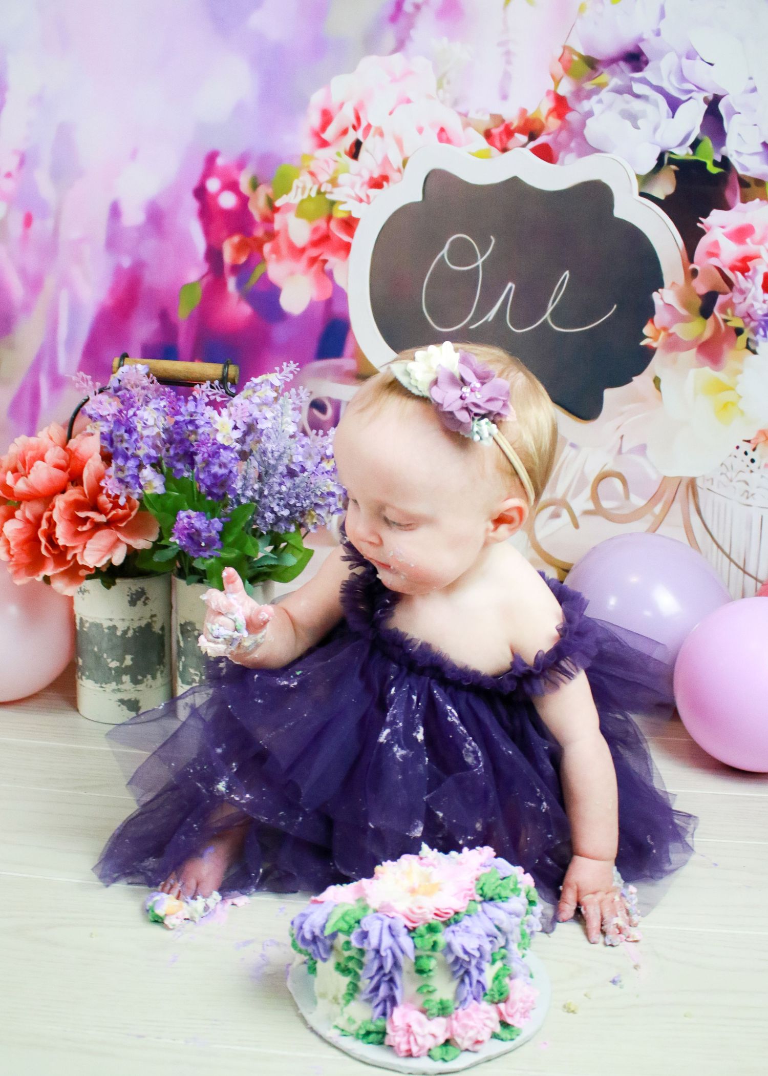 Purple tulle dress cake smash session with floral decorations.