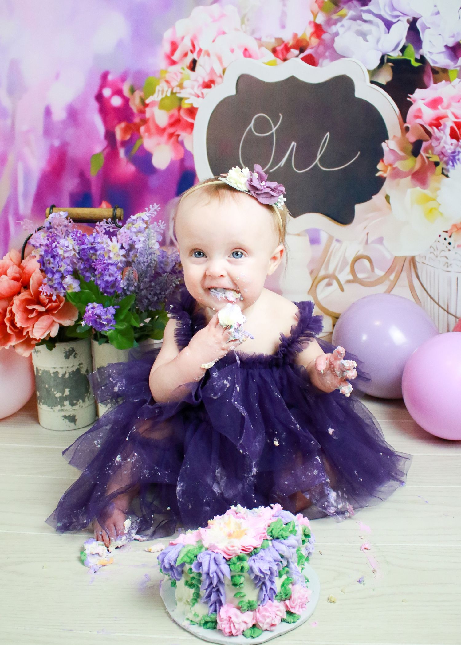 Cake smash photography with purple tulle dress and pink flowers.