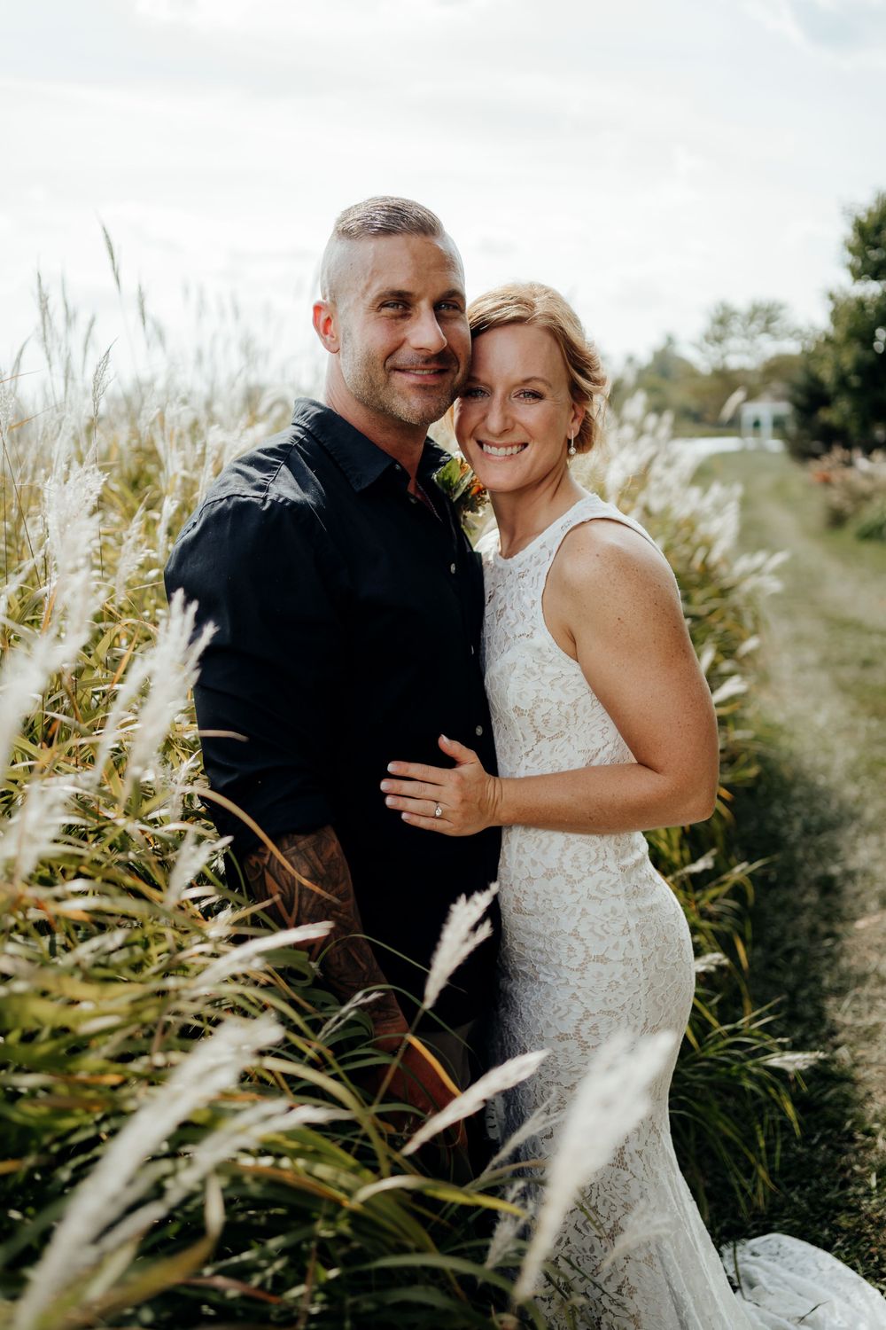 Bride and groom posing for the camera next to beautiful wheat field.
