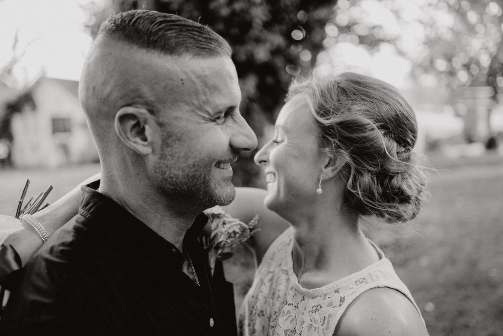 Black and white image of bride and groom laughing with each other.