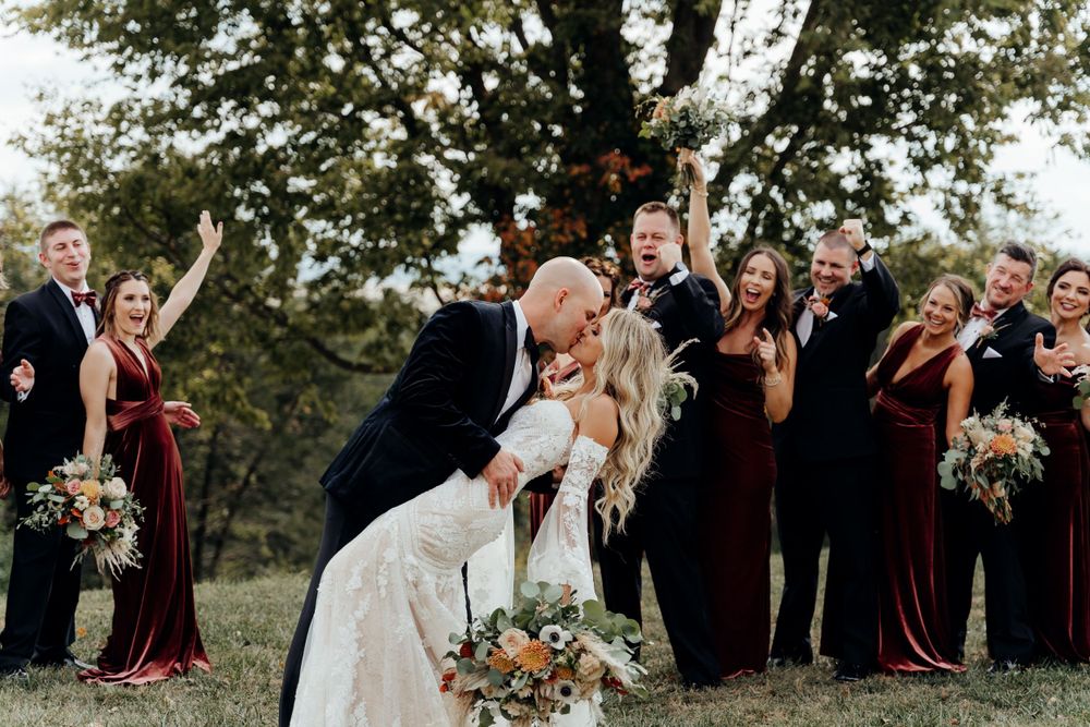Bride being dipped by groom for a kiss between the bridal party.