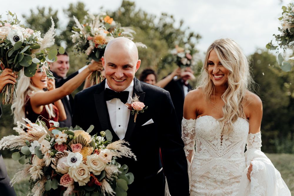 Bride and groom sharing a happy moment, smiling with bridal party.