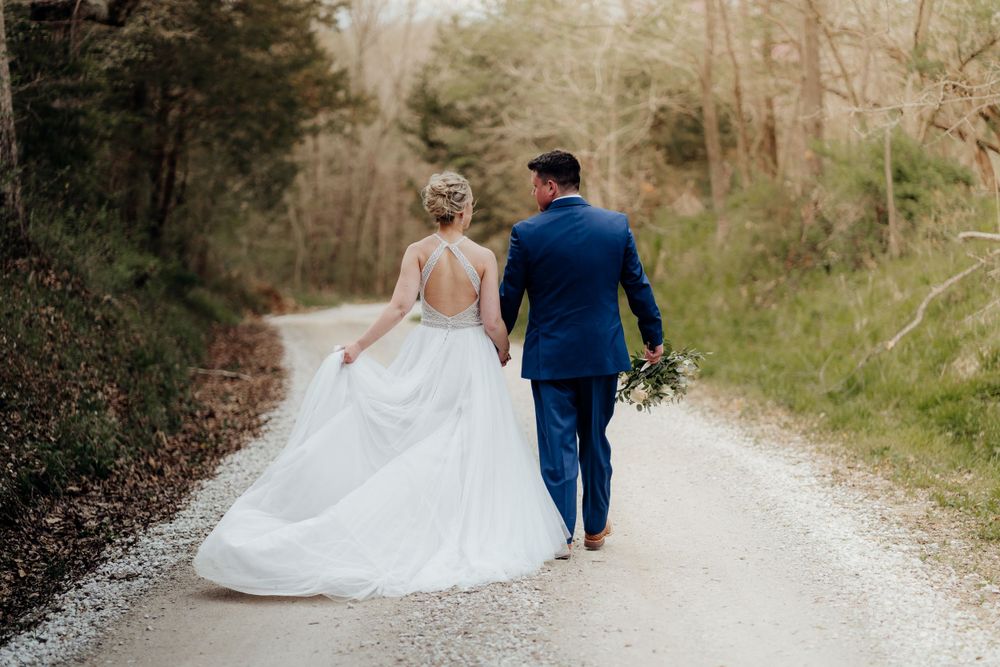Bride and groom walking away down a gravel road, looking at each other.