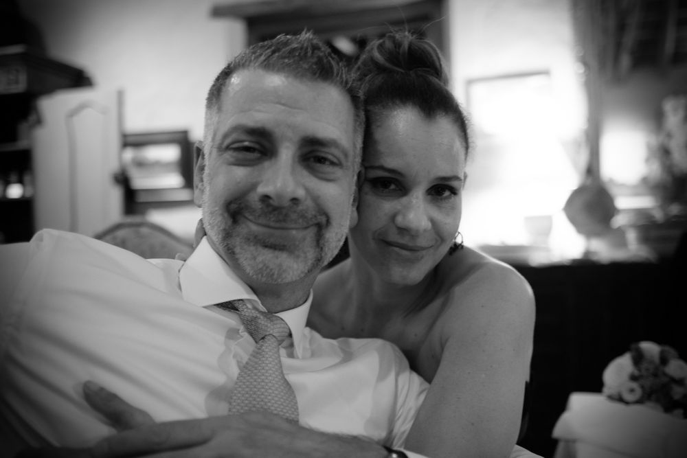 Black and white portrait of a smiling couple embracing warmly at a wedding celebration indoors.