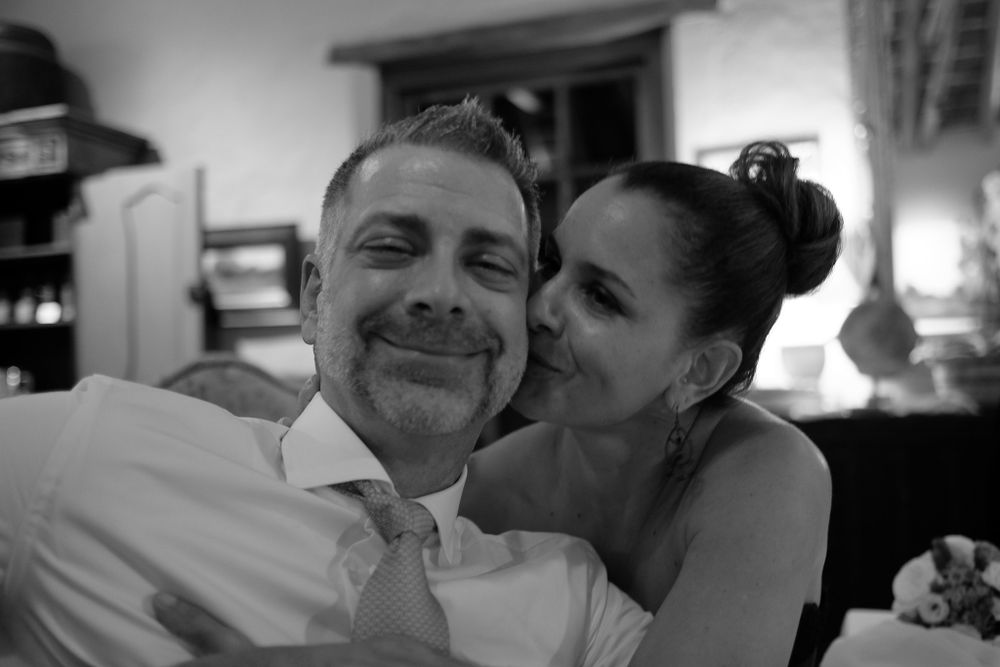 Black and white image of a joyful couple smiling and embracing affectionately at a wedding event.