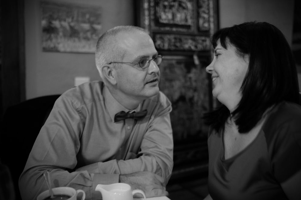 Older couple in conversation sharing a warm moment over coffee at a decorated table.