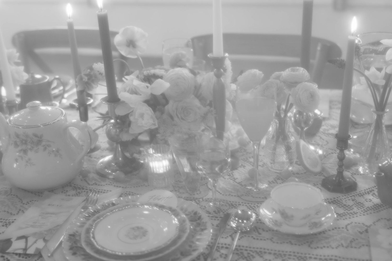 Elegant table setting with lit candles, floral arrangements, and fine china place settings.
