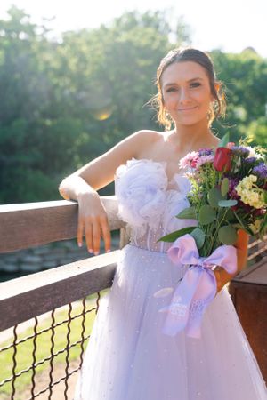 Elegant bridal portraits on wooden deck featuring white tulle gown and colorful floral bouquet.