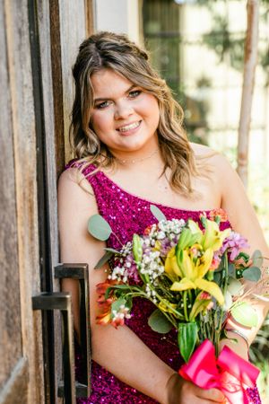 Bridesmaids in magenta sequined dresses hold vibrant lily and rose bouquets during outdoor wedding photos.