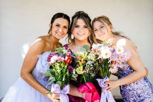 Group photo with purple bridesmaid dresses and colorful flower bouquets.