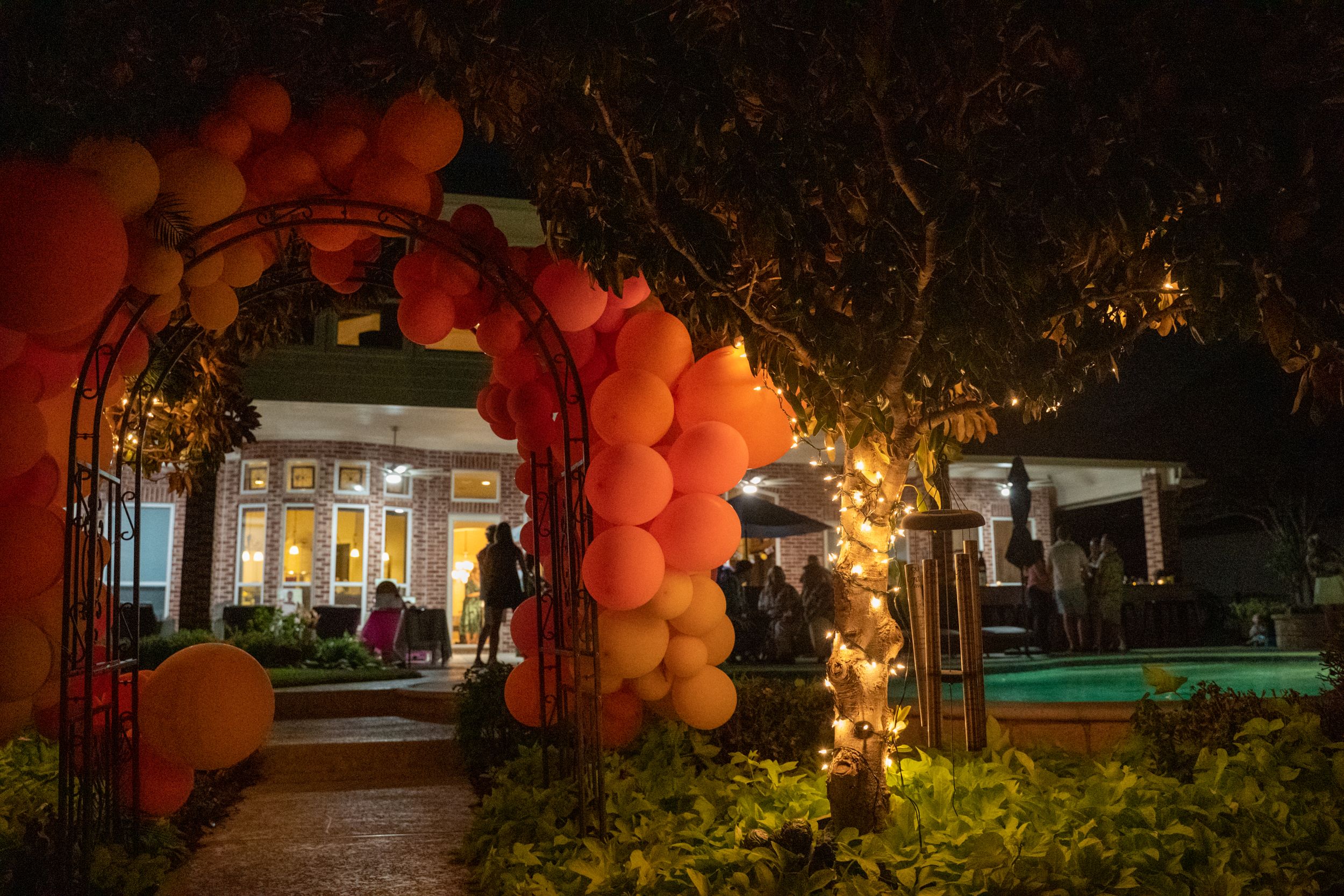 Outdoor evening event space decorated with orange balloon arches and ambient lighting.