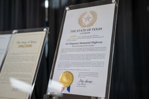 Official Texas state documents and certificates with gold seals displayed on a wall.
