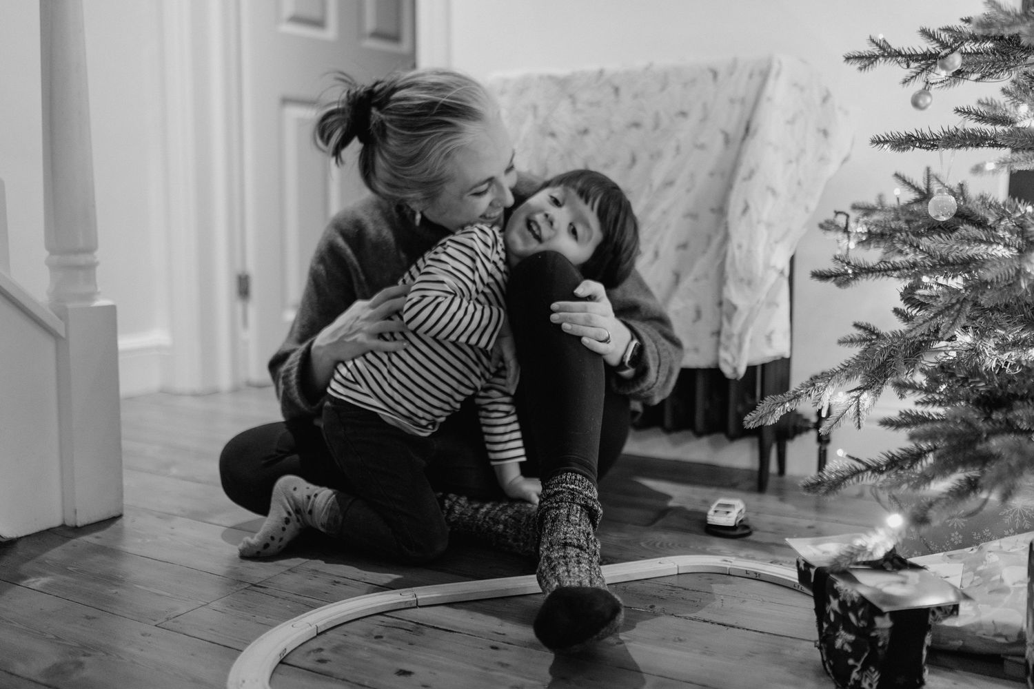 Natural photo of 
Mother and Son laughing and sitting by the Christmas tree