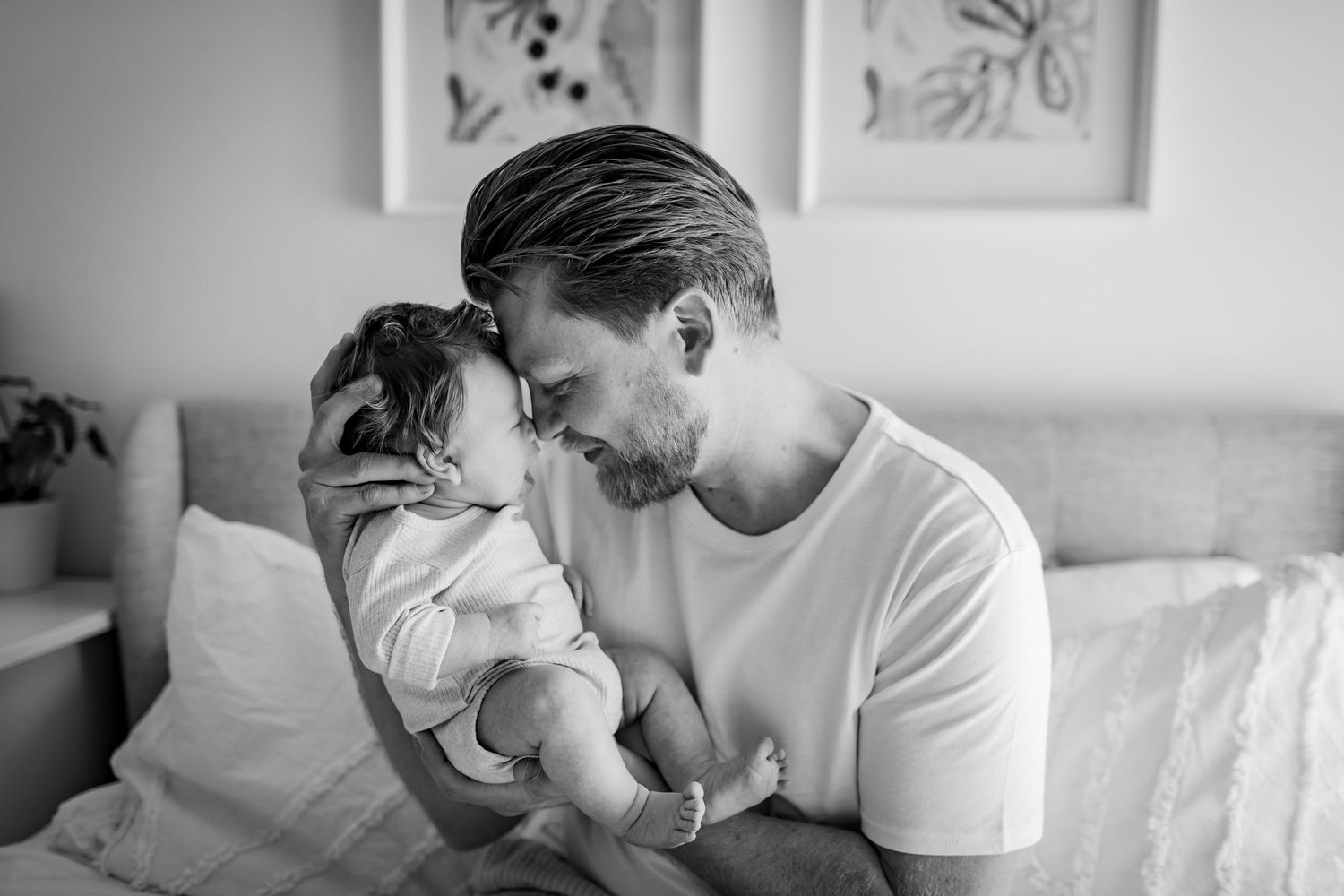 Intimate black and white portrait of parent and baby sharing a tender moment.