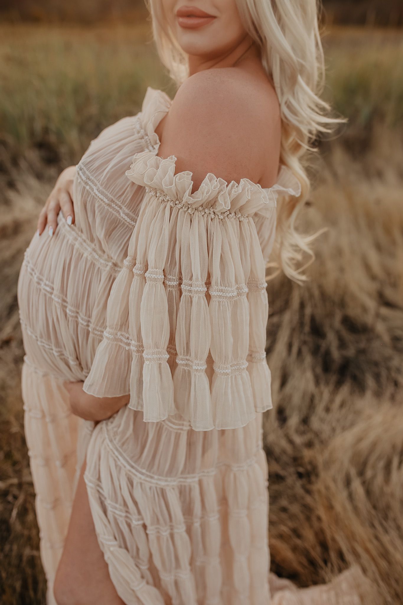 Delicate white ruffled dress details shown in warm natural lighting against a rustic backdrop.