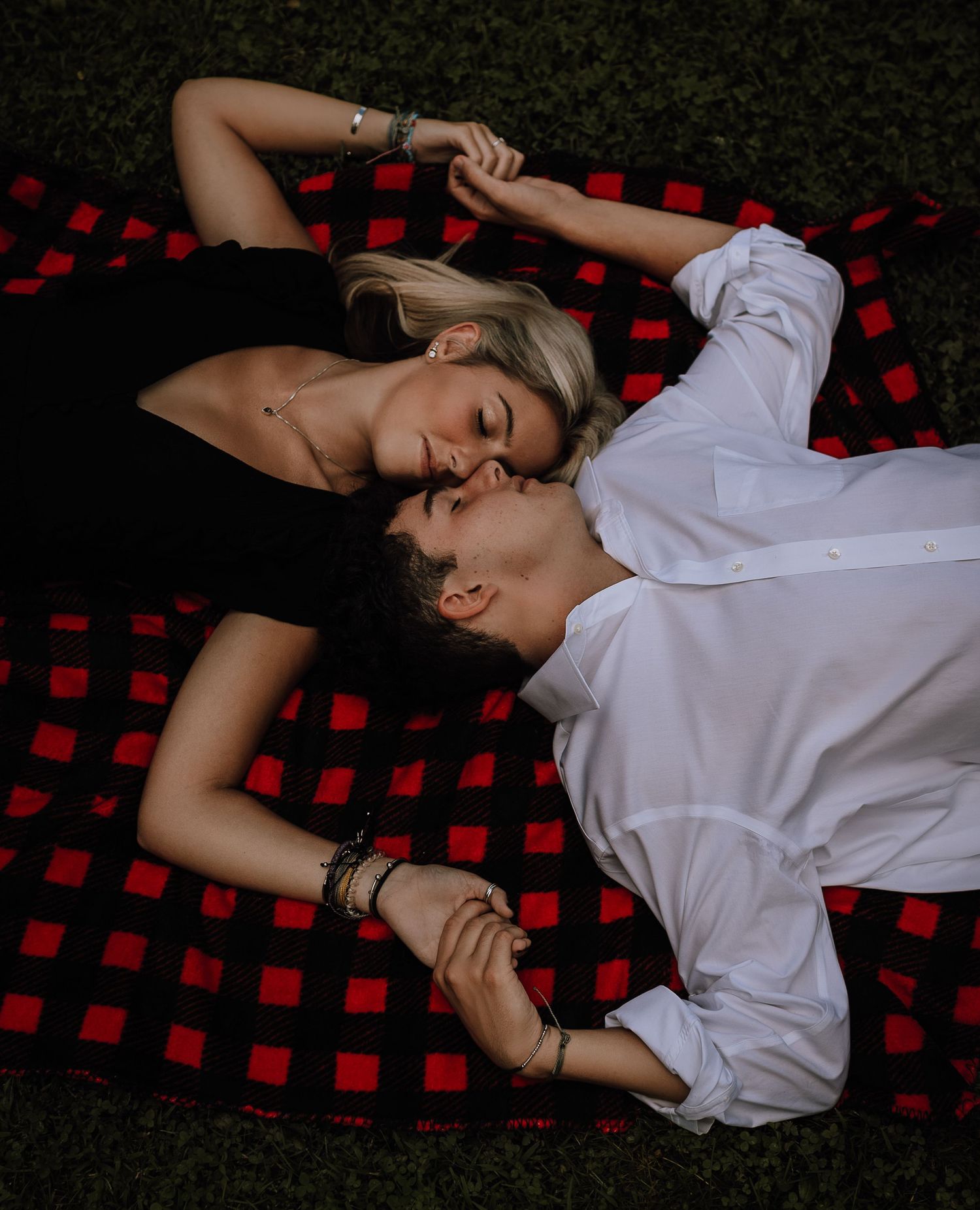 Person in white shirt lying on red and black plaid blanket in artistic portrait series.